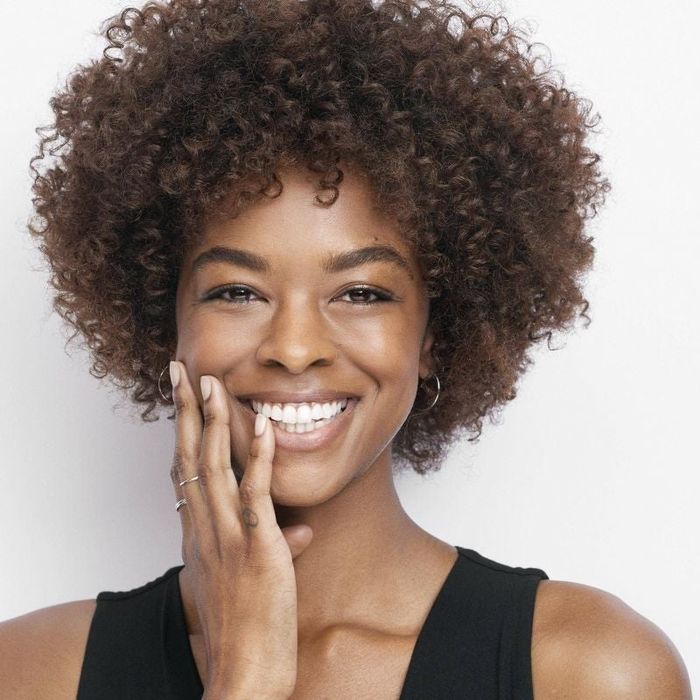A person with curly hair showcasing smooth, clean skin