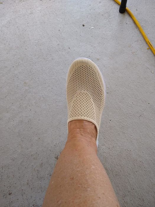 A knit slip-on shoe worn by a reviewer, displayed on a concrete surface, ideal for casual outings.