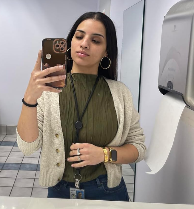 Someone taking a selfie wearing a cardigan over a green ruffled tank top.