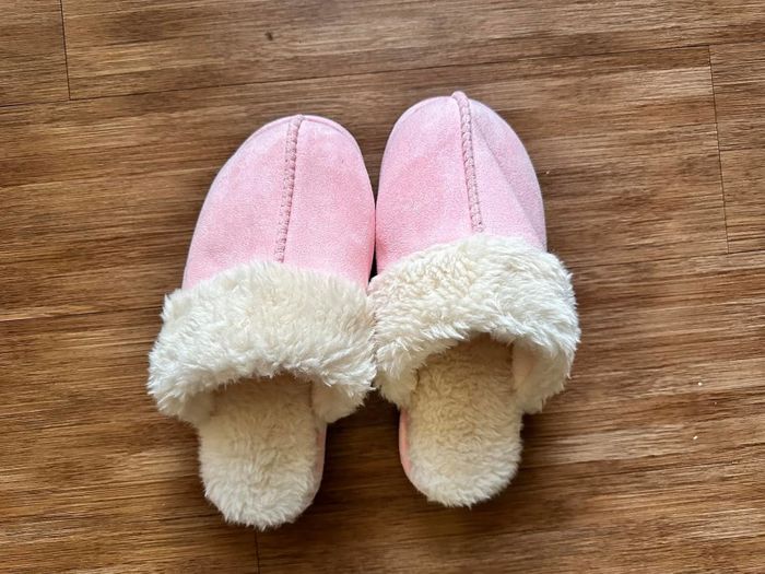 A reviewer’s fuzzy slippers placed on a wooden floor, perfect for a cozy and laid-back indoor vibe.