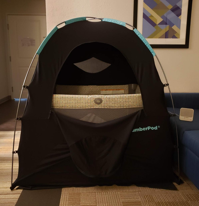 A reviewer’s photo of the SlumberPod with the front zip door open, revealing a playpen inside
