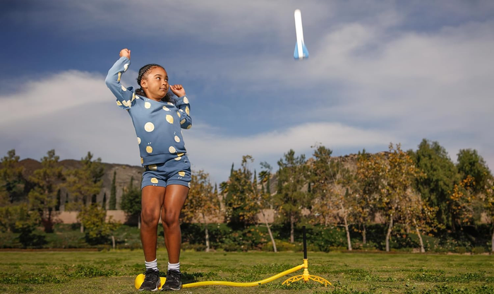 A child enthusiastically launching a toy rocket high into the sky