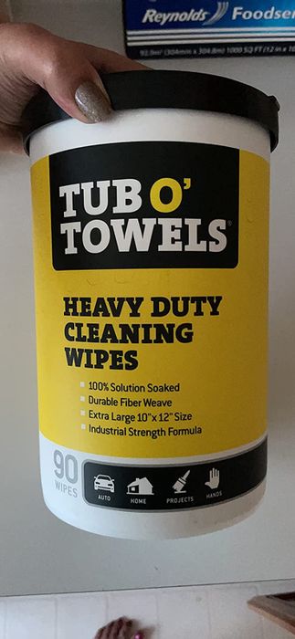 A reviewer showing off their Tub O' Towels heavy-duty cleaning wipes.