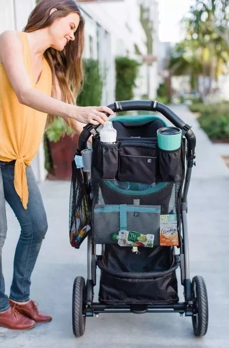 Person using a stroller organizer with multiple compartments while out and about