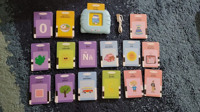 Children's language learning set features 18 illustrated flashcards and a blue electronic reader connected by a white cable