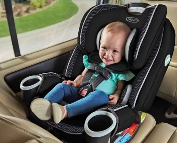 A toddler sitting happily in a car seat, with a focus on its safety features, perfect for a shopping guide on car seats.