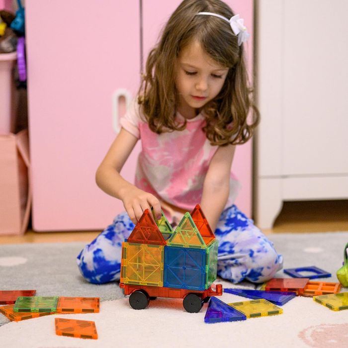 A young child constructing a colorful structure using magnetic tiles