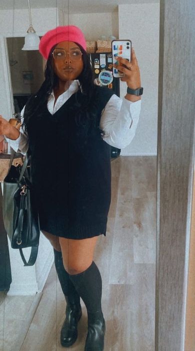 reviewer styling a black sweater vest over a white collared shirt, paired with a red beret, black shoes, and knee-high socks