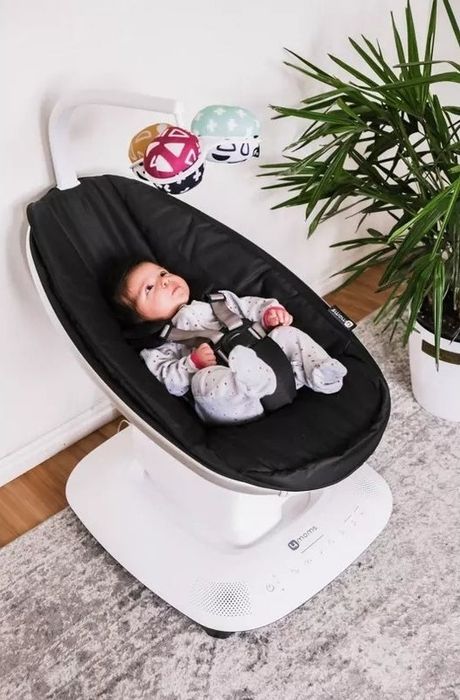 Baby in a sleek bouncer with hanging toys, set up in a cozy home environment, for a guide on baby gear shopping