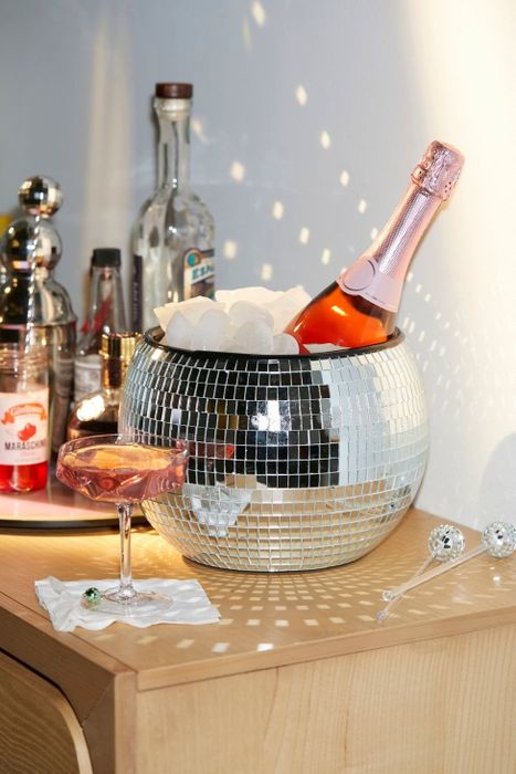 The round disco ball ice bucket, filled with ice and a bottle of champagne