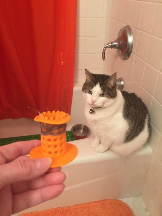 An orange silicone drain stopper with pet hair collected on its surface.