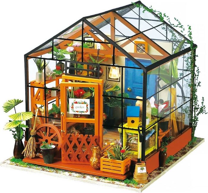 The completed miniature greenhouse kit featuring plants, a glasshouse structure, shelves, furniture, and other delightful details