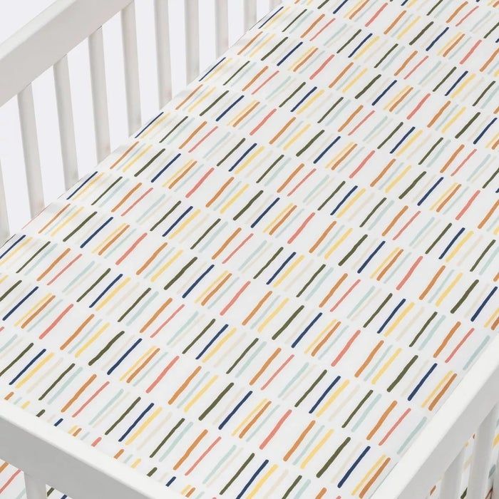 Crib featuring a vibrant, multicolored striped mattress cover.