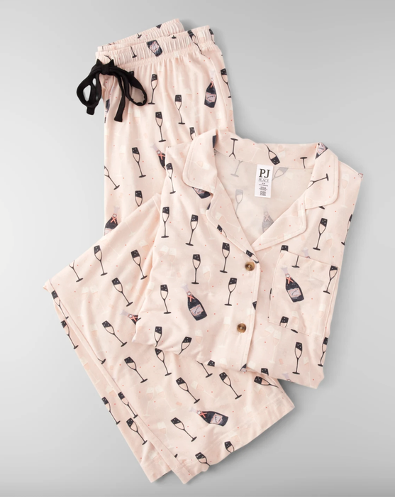 A flatlay showing the soft blush pink PJs folded neatly, complete with champagne bottles and flutes
