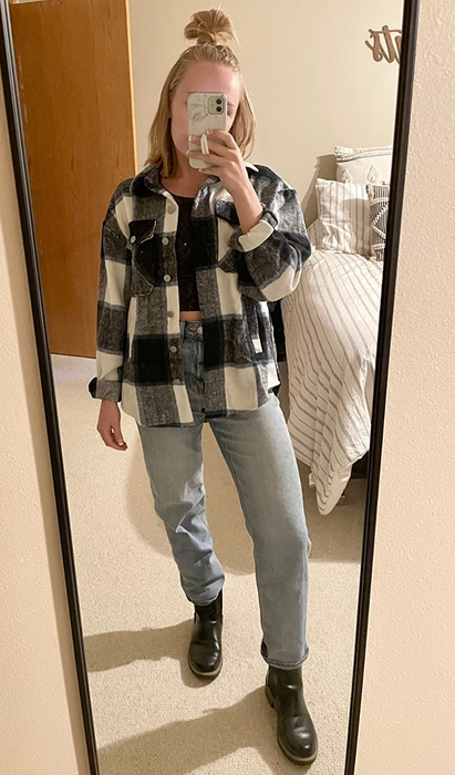a reviewer styling the plaid shacket in white and navy, layered over a crop top and denim jeans