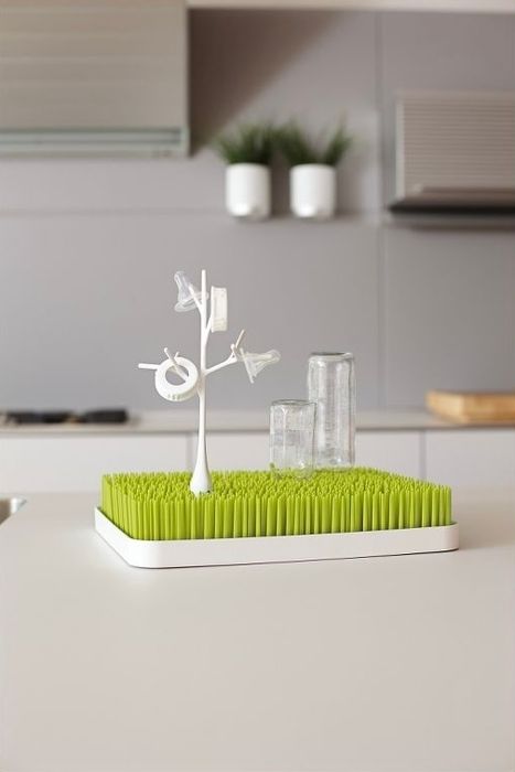 A dish rack with bottles and a cup drying on a kitchen counter