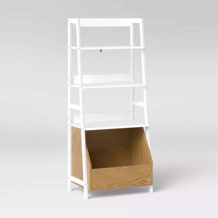 A white bookshelf with a stylish angled bottom bin, featuring a contrasting wood finish.