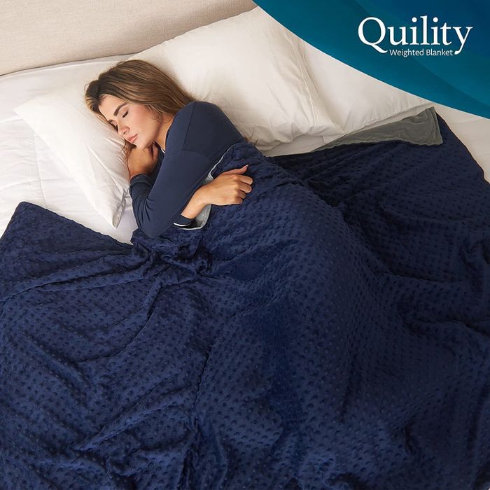 A model resting under the cozy grey and blue weighted blanket