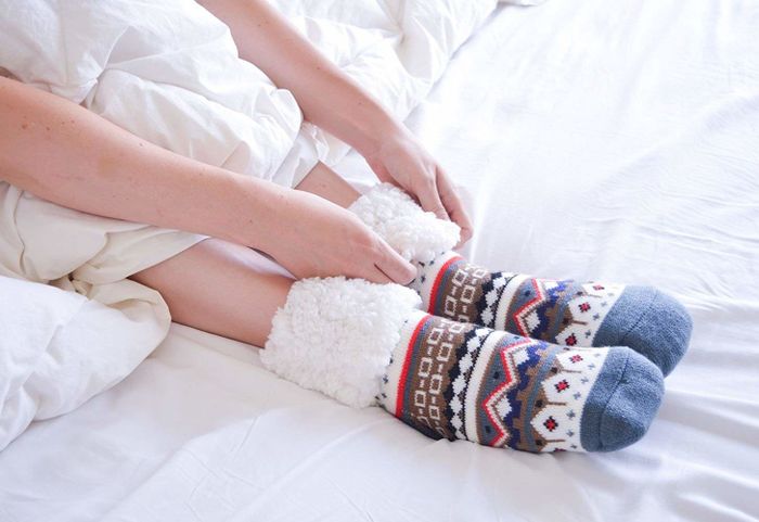 A model showcasing the Fair Isle slippers, with the cuffs rolled down to reveal the plush sherpa lining