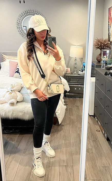 A reviewer wearing the cream-colored sweatshirt