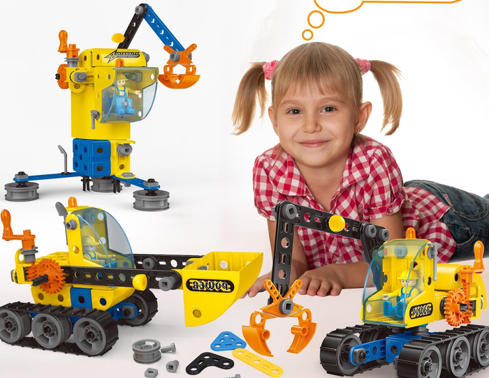 A young child playing with modular construction toys, including a crane and bulldozer