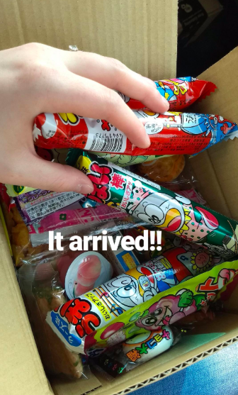 A reviewer holds up a box filled with candy