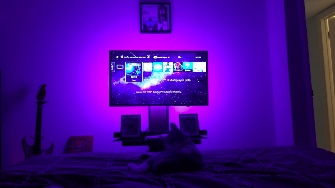 A reviewer's image of a TV with vibrant purple LED lights glowing behind it