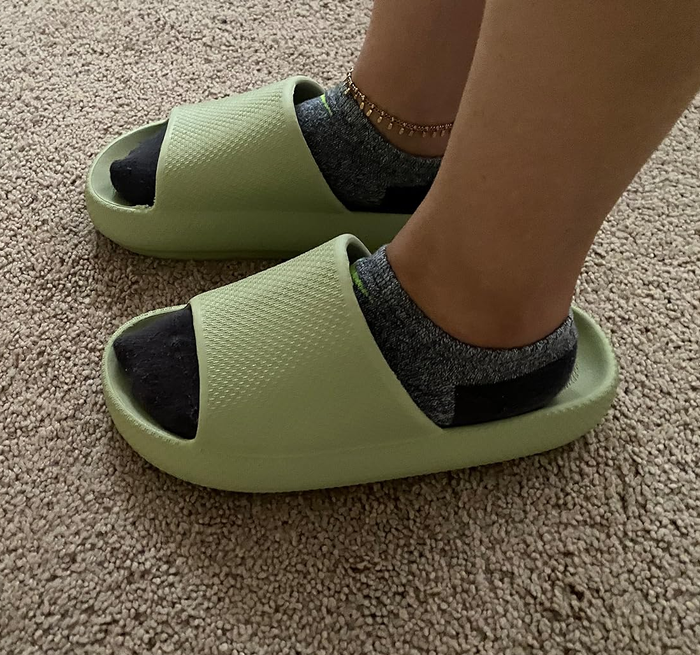 A reviewer wearing the slide in light green with socks