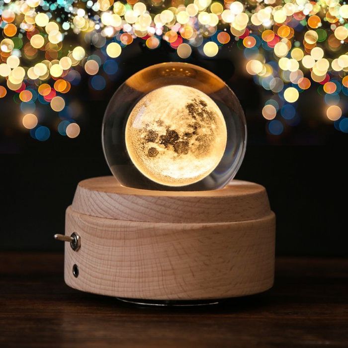 A wooden base with a clear glass sphere and a moon inside