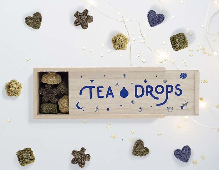 A wooden box containing pressed tea in fun shapes like stars, flowers, and hearts.