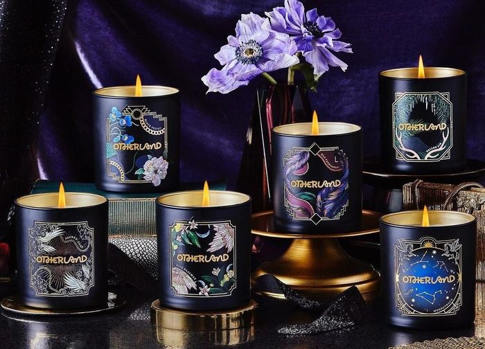 Six black candles adorned with winter-themed illustrated labels