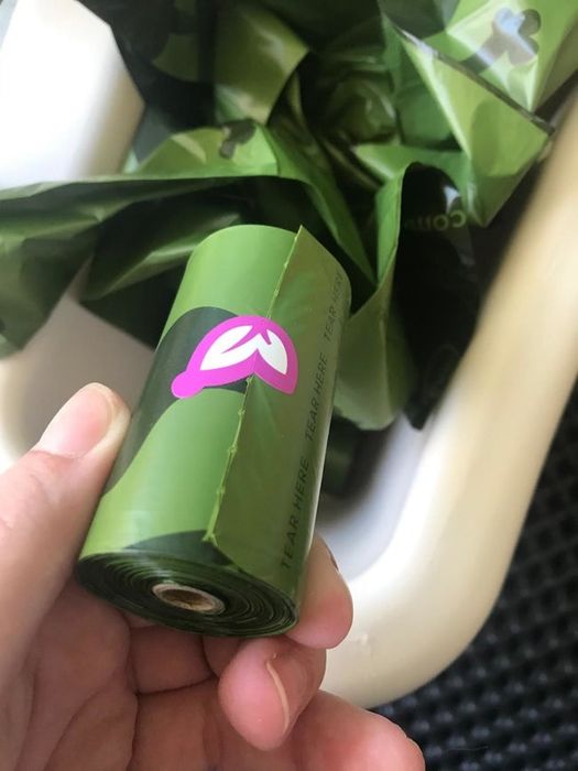 A reviewer holding a roll of green poop bags in their hand