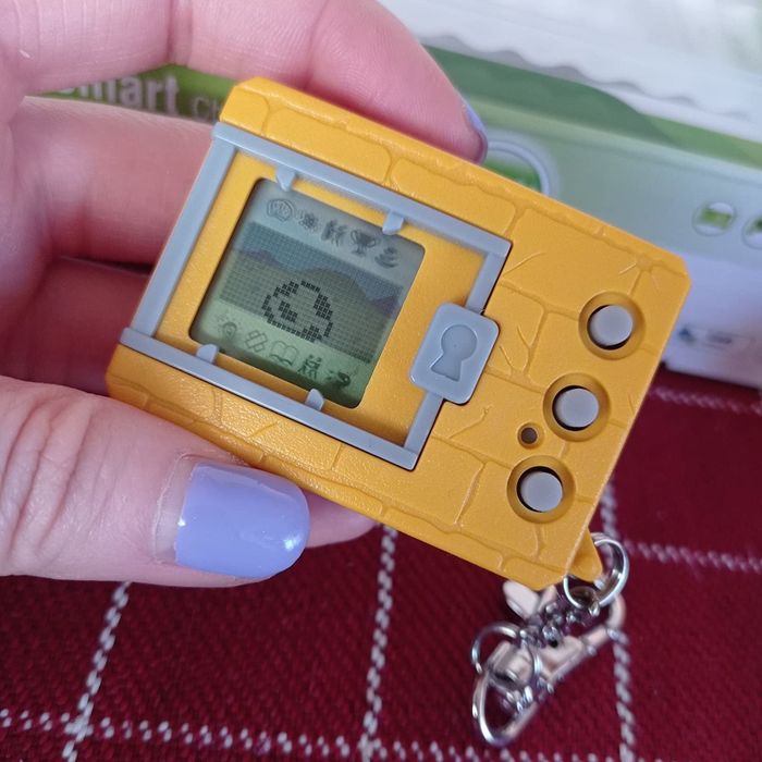 A yellow and gray Digimon with a monster egg shown on the screen.