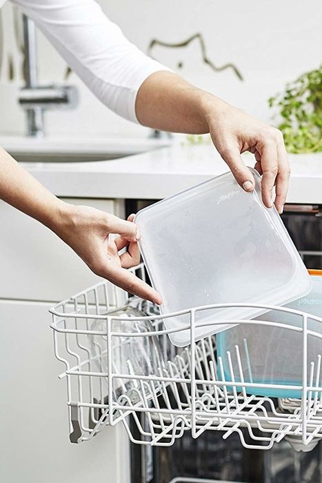 Hands placing the silicone bag into the top rack of the dishwasher for cleaning