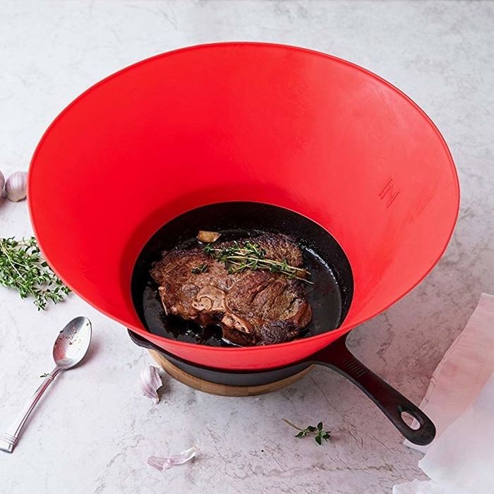 Steak cooked in a cast-iron skillet with a red Frywall extending over it