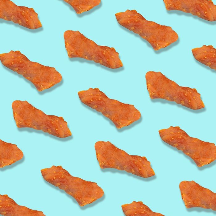 Small pieces of salmon nuggets scattered on a blue background, ready for your cat to enjoy.