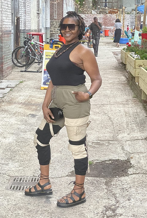 The reviewer, wearing a casual sleeveless top and cargo pants with knee patches, paired with the strappy Dr. Martens sandals