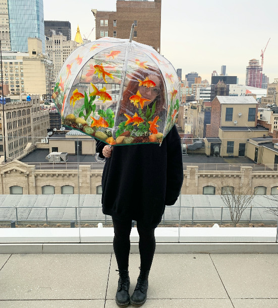 shopping writer Mallory Mower using a clear, round umbrella adorned with fish designs