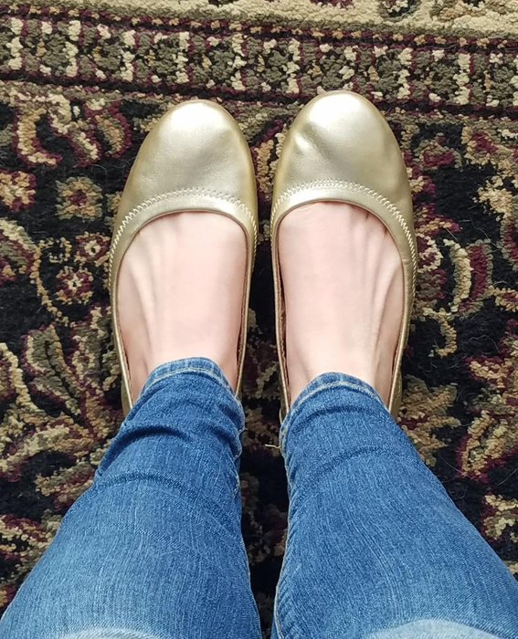 A reviewer wearing the gold ballet flats