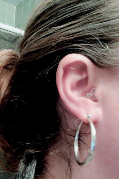 A close-up shot of the earplugs in a reviewer's ear, with the clear tail blending in almost completely