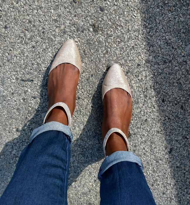 A person wearing shimmery pointy-toe flats