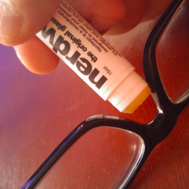 A reviewer applying Nerdwax to their glasses for a better grip