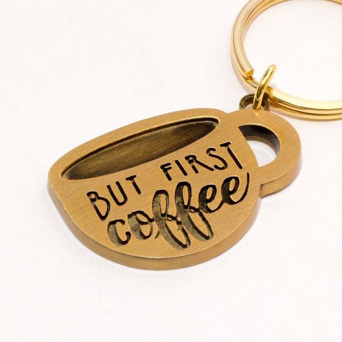 A coffee mug charm that reads 'But first, coffee'