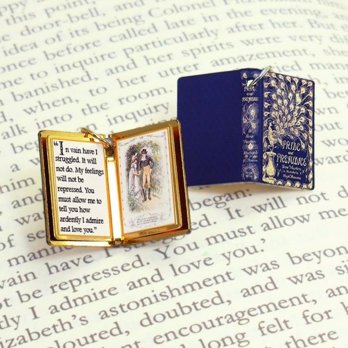 A book charm of Pride and Prejudice featuring a blue cover with a peacock design.