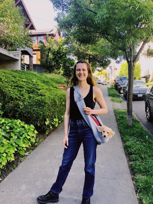 A reviewer wearing the sling with a small dog inside it.