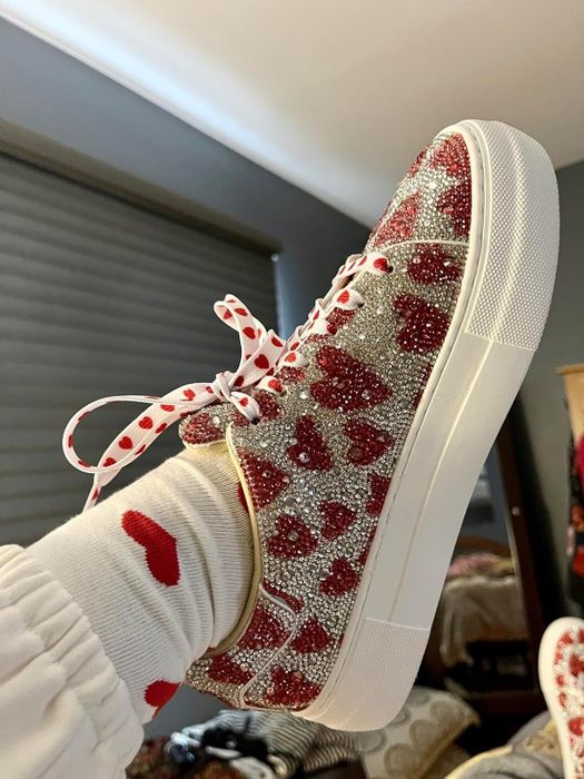 A person wearing sneakers adorned with a glittery heart design