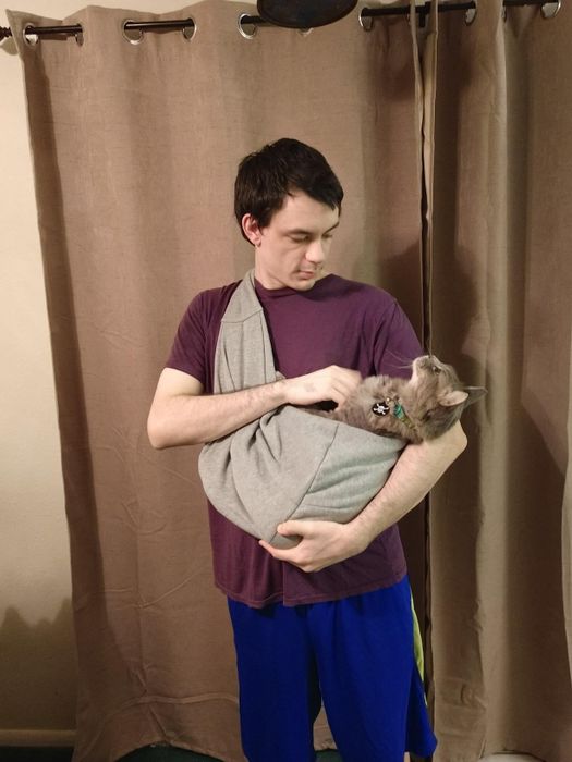 A reviewer wearing the sling with a cat inside it.