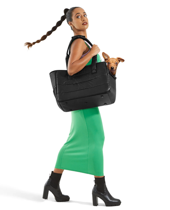 A model sporting the tote on their shoulder with a dog nestled inside