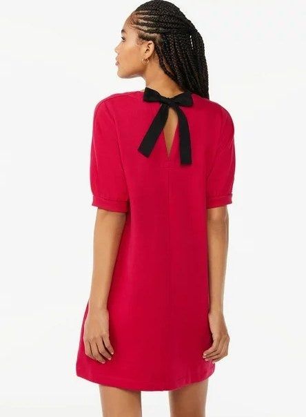 The model is showing off the bow-back detail of the cerise red dress.