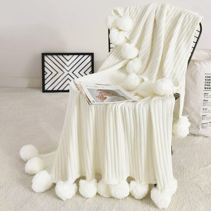 blanket adorned with large, fluffy pom-poms